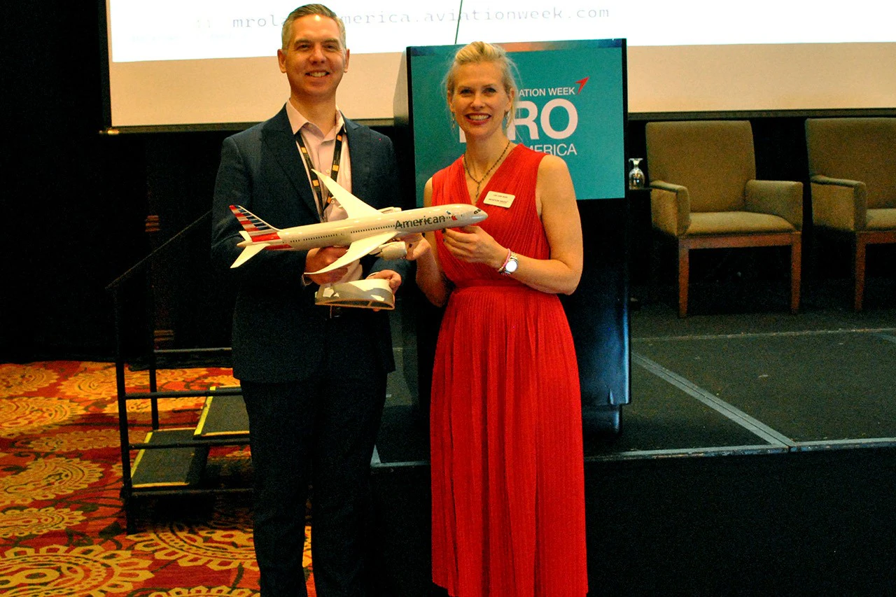 2 people taking picture with dummy plane
