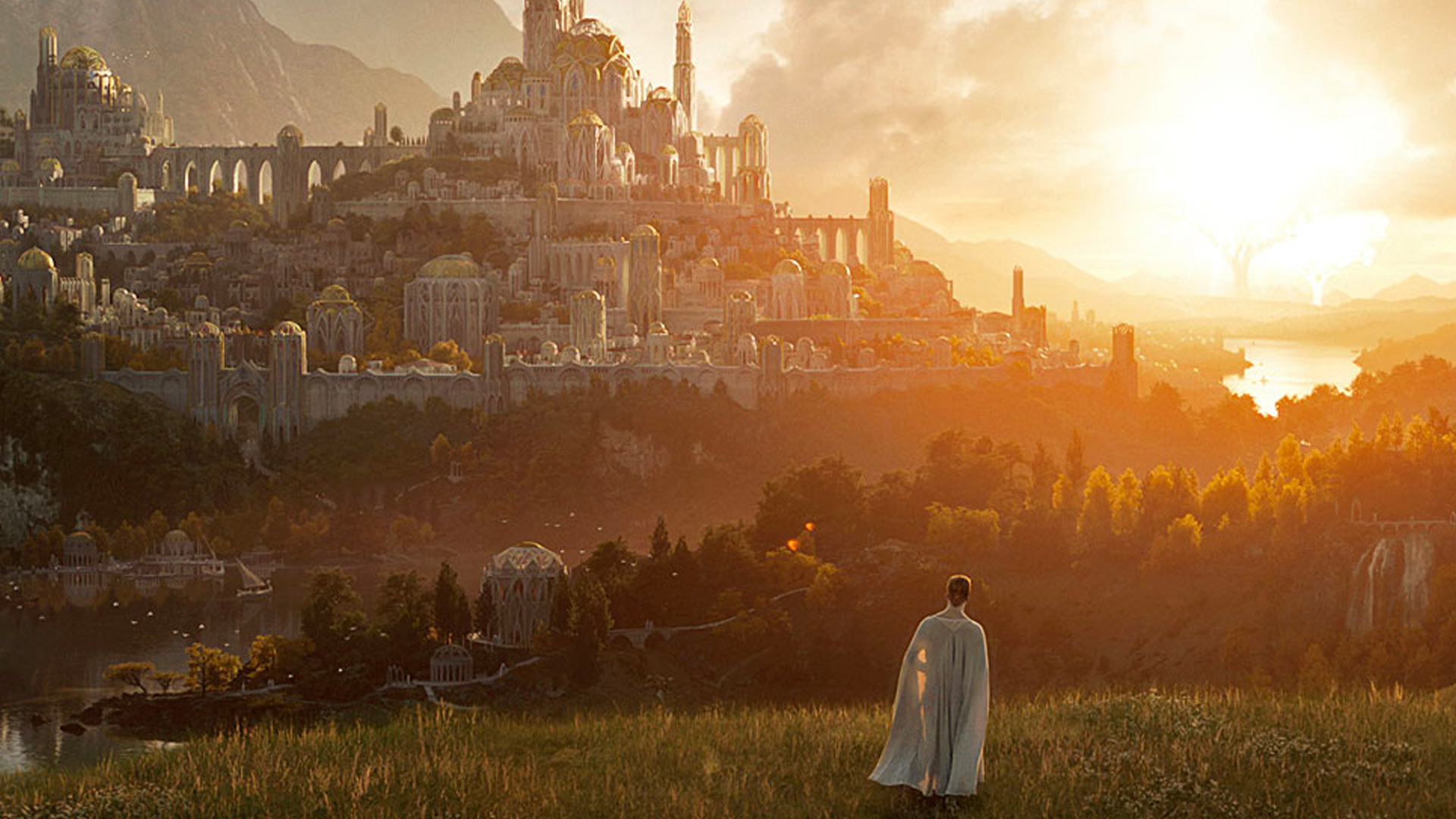 A person stands in a white cloak at sunset looking at a large castle in the distance