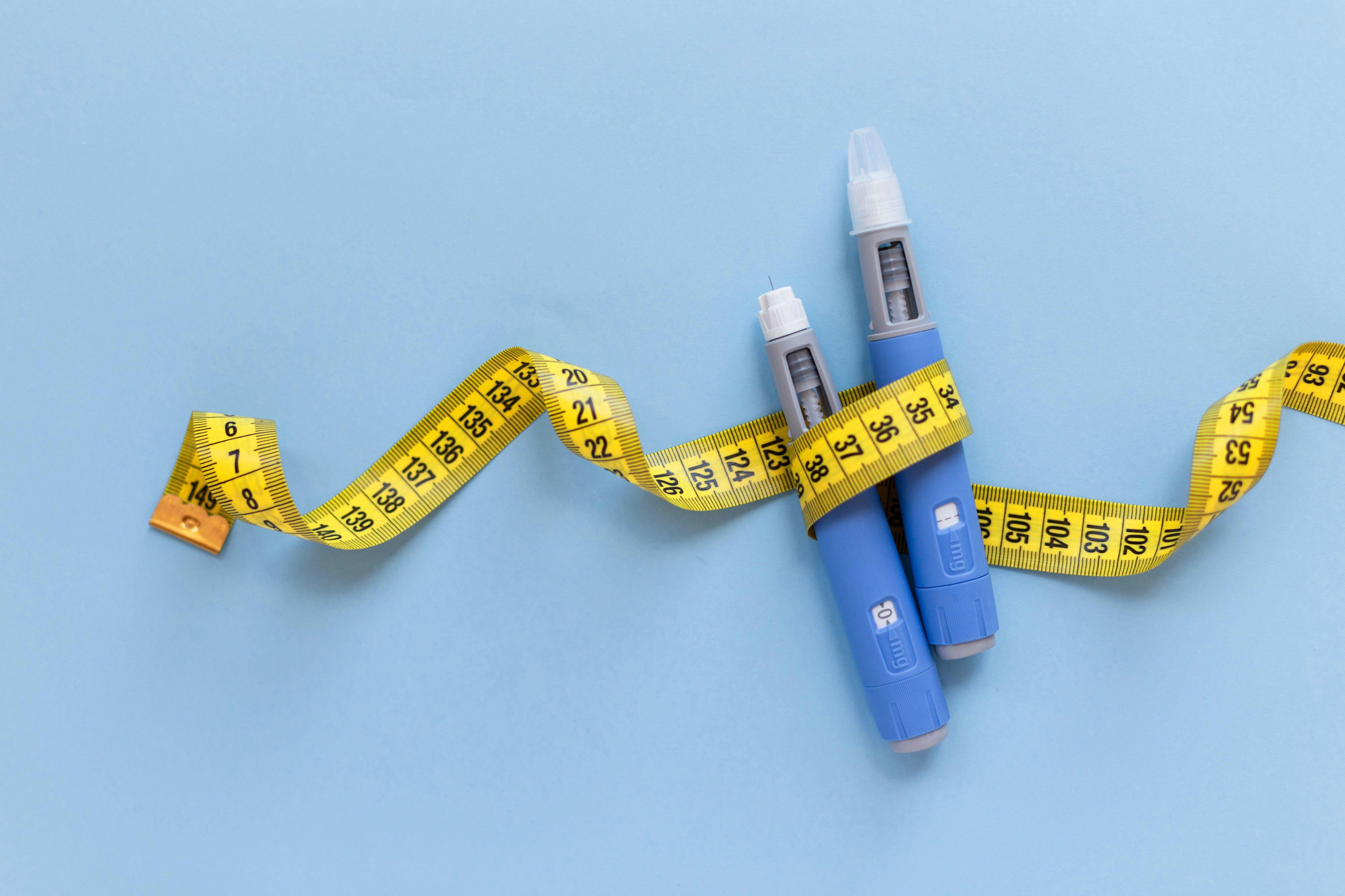 a measuring tape wrapped around some injectables for obesity therapeutics