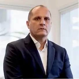 Marco Bego, palestrante do Healthcare Innovation Show, em foto de perfil vestindo terno escuro e camisa branca.