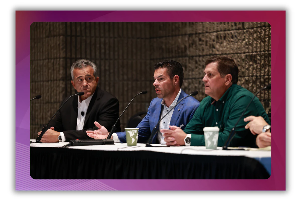 A photo of three men sitting at a table onstage participating in a panel discussion at MSP Summit