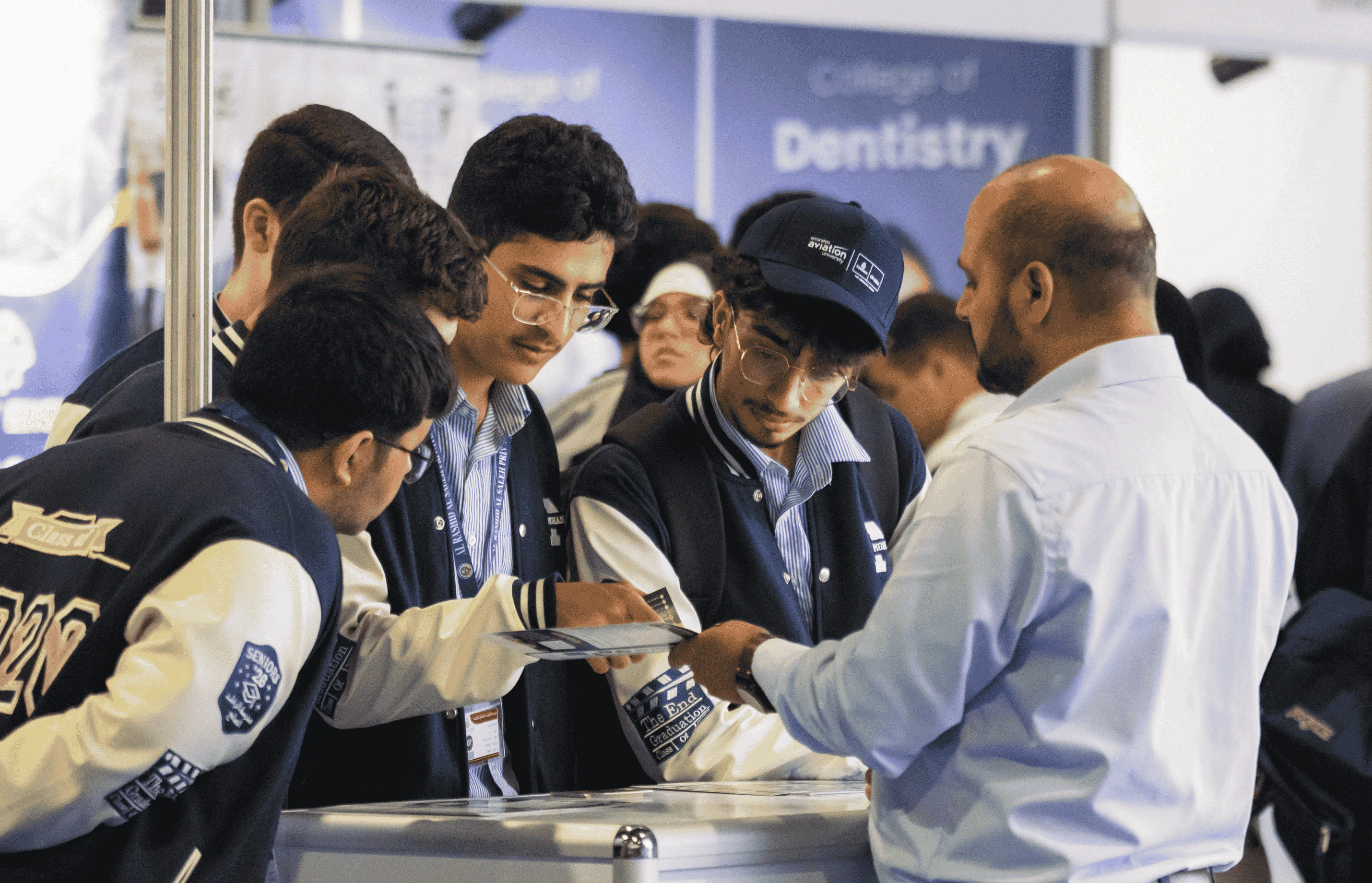 Students interacting with university admissions staff at NAJAH, receiving guidance on enrolment and programs at an engaging educational fair with diverse attendees.