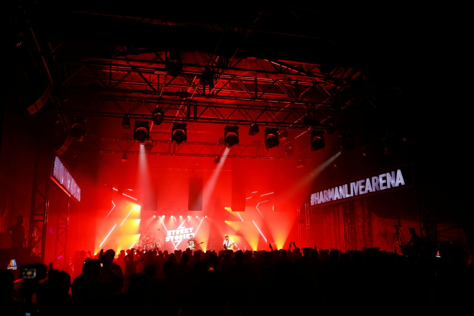 Crowd enjoying a live music performance under vibrant red stage lighting at HARMAN Live Arena