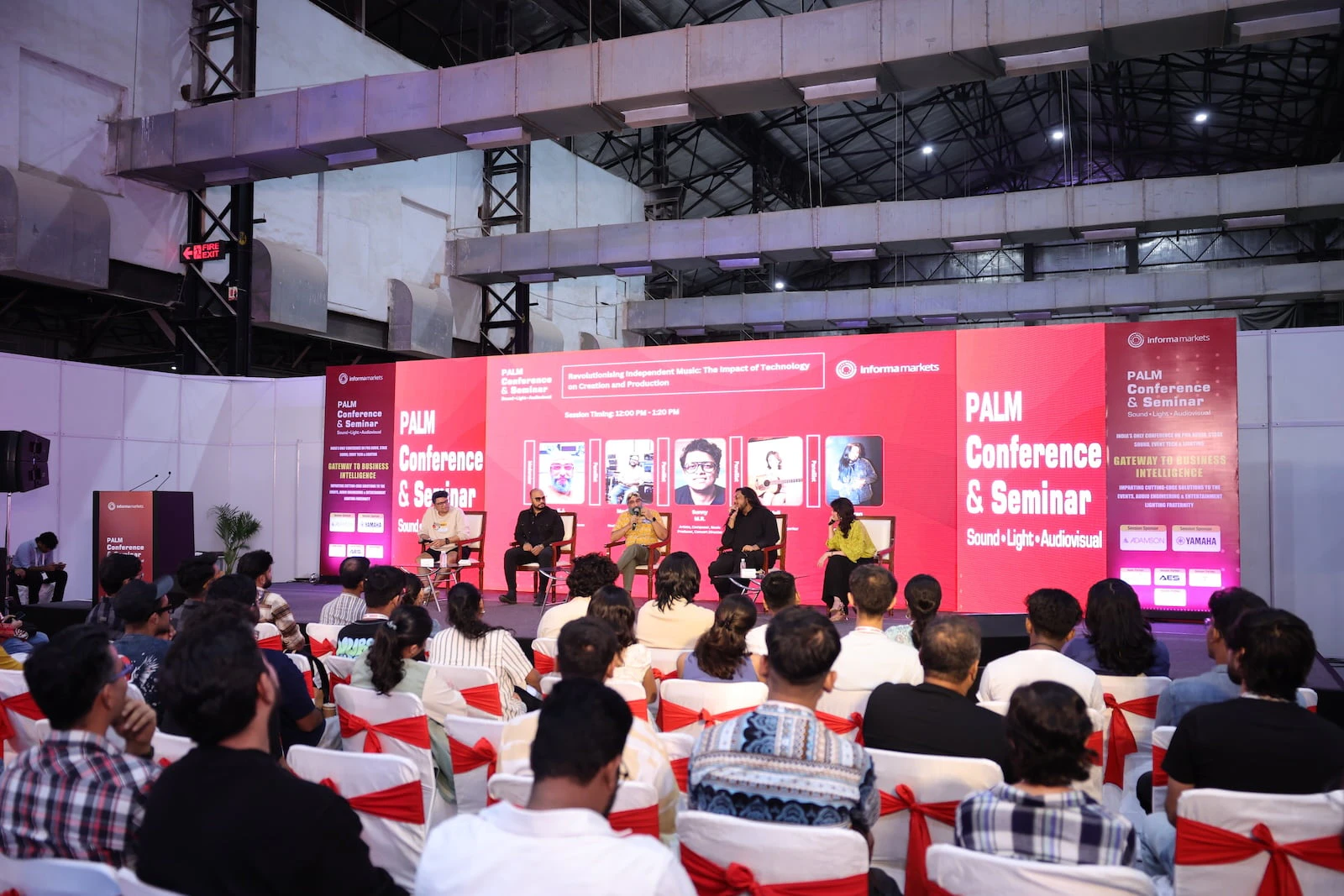 Panel discussion at PALM Conference, with industry experts speaking on stage to a seated audience about sound, light, and audiovisual topics.