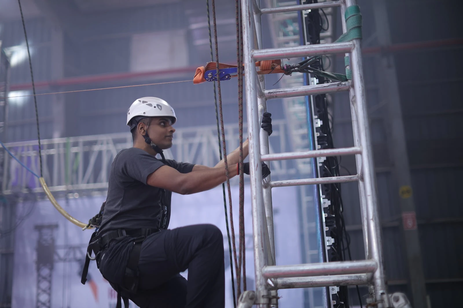 Technician wearing safety helmet working on stage rigging setup during PALM Expo Live Rigging Workshop