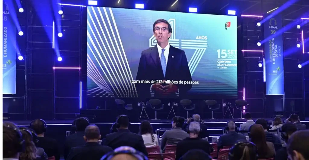 Transmissão de autoridade de Portugal no telão principal do evento HIS para auditório lotado.