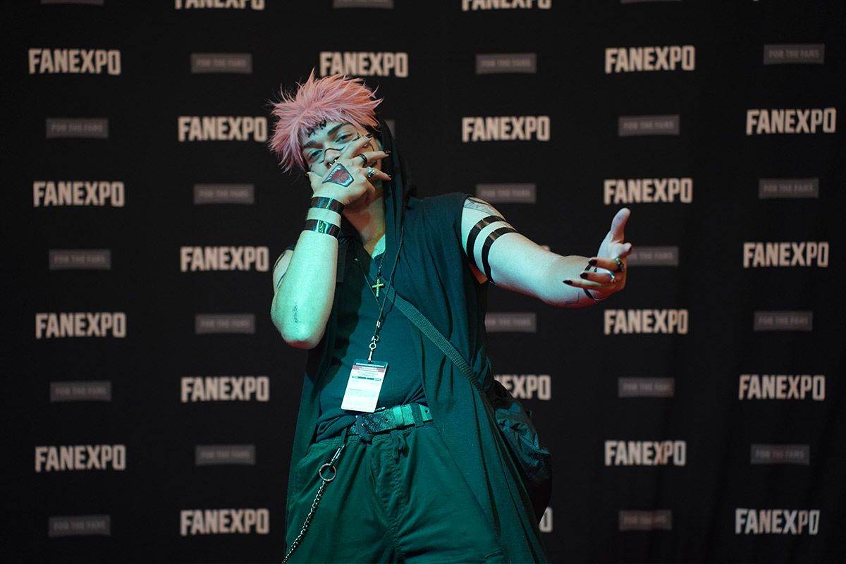 a cosplayer poses with hand out stretched and other hand covering mouth