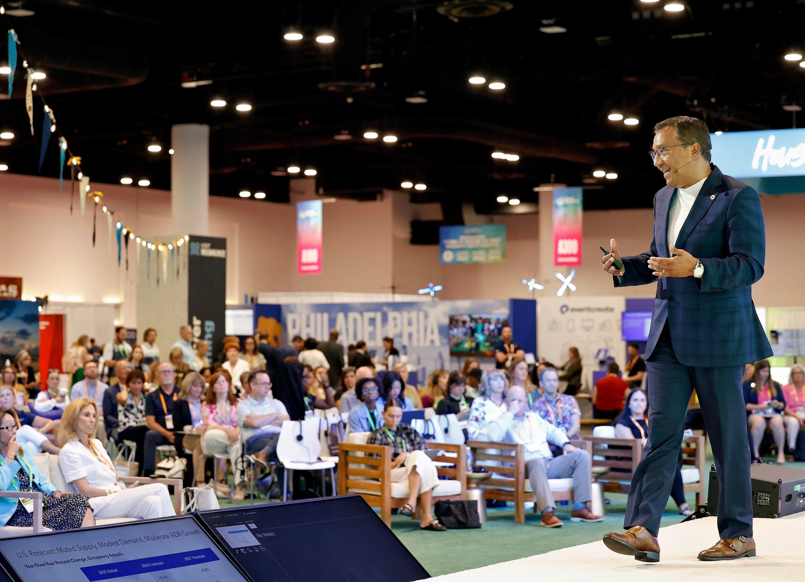 A male speaker standing on stage discussing educational content at a conference