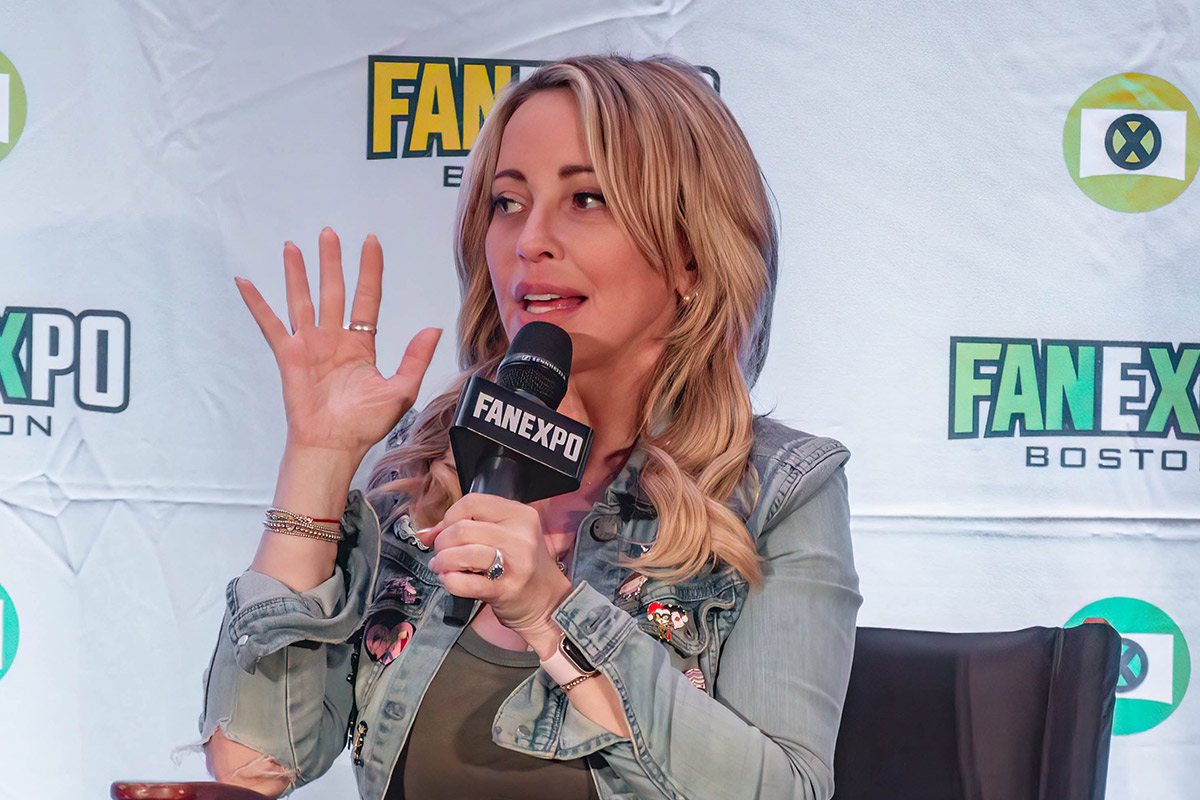 Tara Strong speaks with hand raised on stage