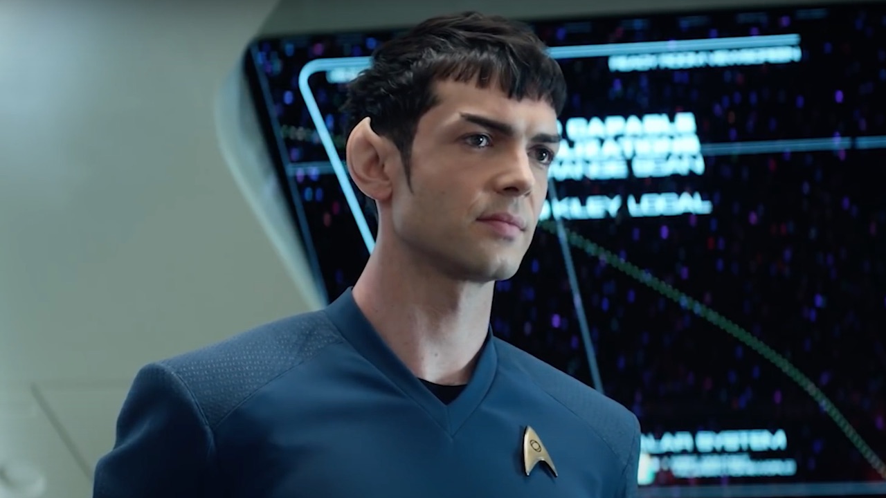 Sponk stands in his blue tunic in front of the map on the starship enterprise.