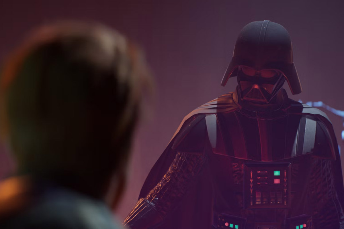 Darth Vader stands ominously in front of Cal Kestis with a glowing red light coming from his lightsaber, not visible