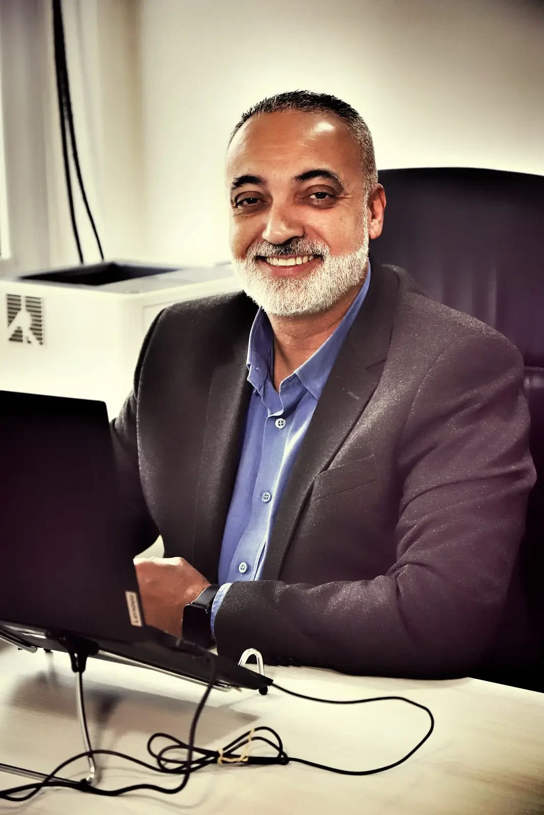 Retrato de Vitor Ferreira, CIO e Presidente do Hospital Infantil Sabará e ABCIS. Um homem de pele madura, com barba grisalha aparada e sorriso aberto, vestindo um paletó cinza sobre uma camisa social azul.