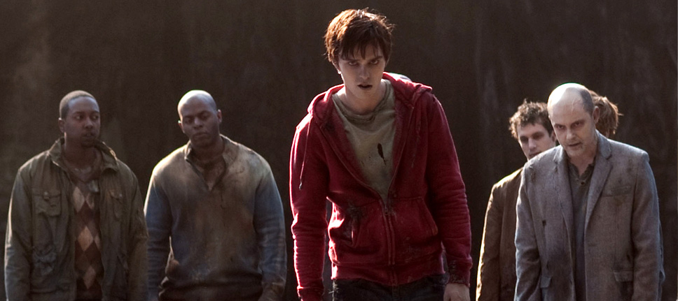 R stands, in his red hoodie, amongst other zombies dressed in a neutral colour palette