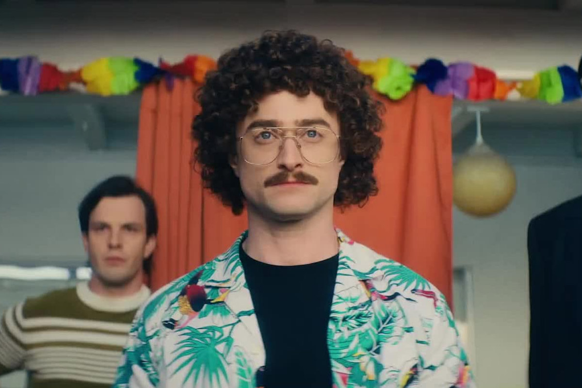 Daniel Radcliffe dressed in a Hawaiian shirt & curly wig as Weird Al