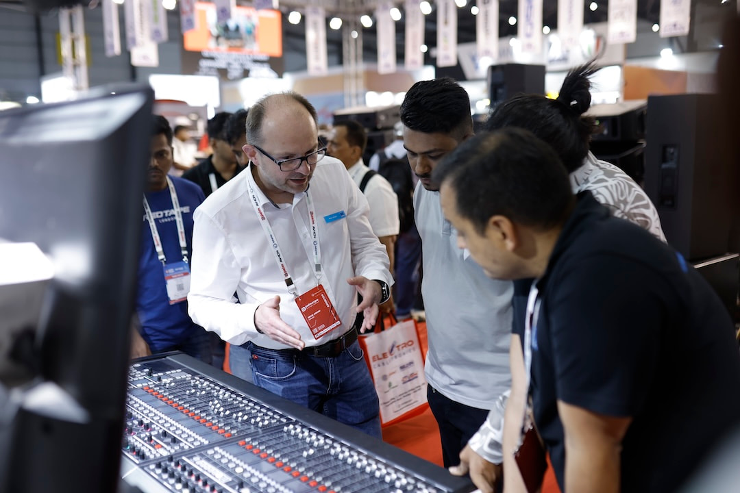 An exhibitor presenting a sound mixing console to attendees at an event