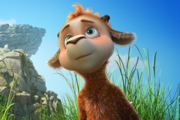 A reddish sheep with green eyes standing in a grassy area with a big boulder behind them.