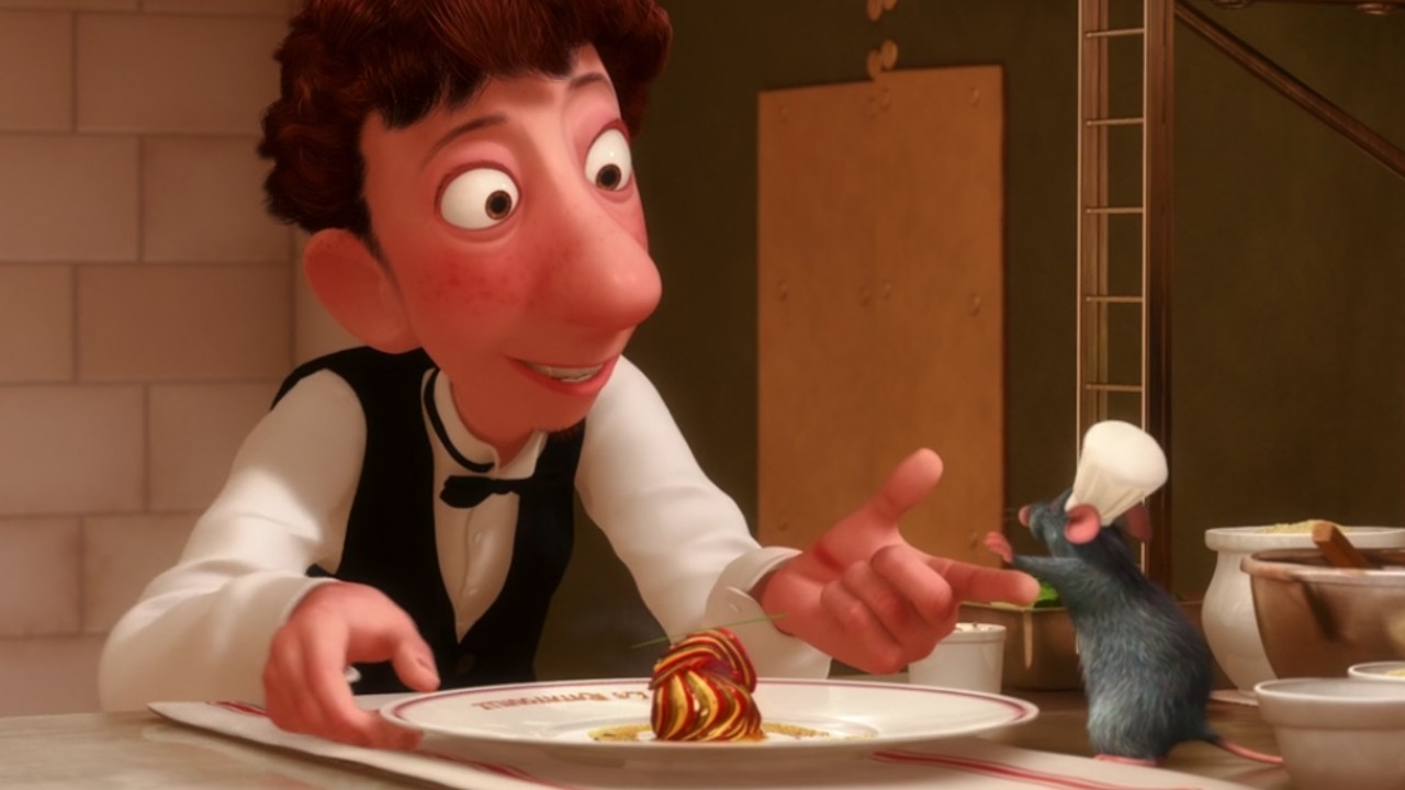 Remy, wearing a tiny chefs hat, hands the final touches for the fresh ratatouille to Linguine, who is dressed ready to serve it to the food critic.