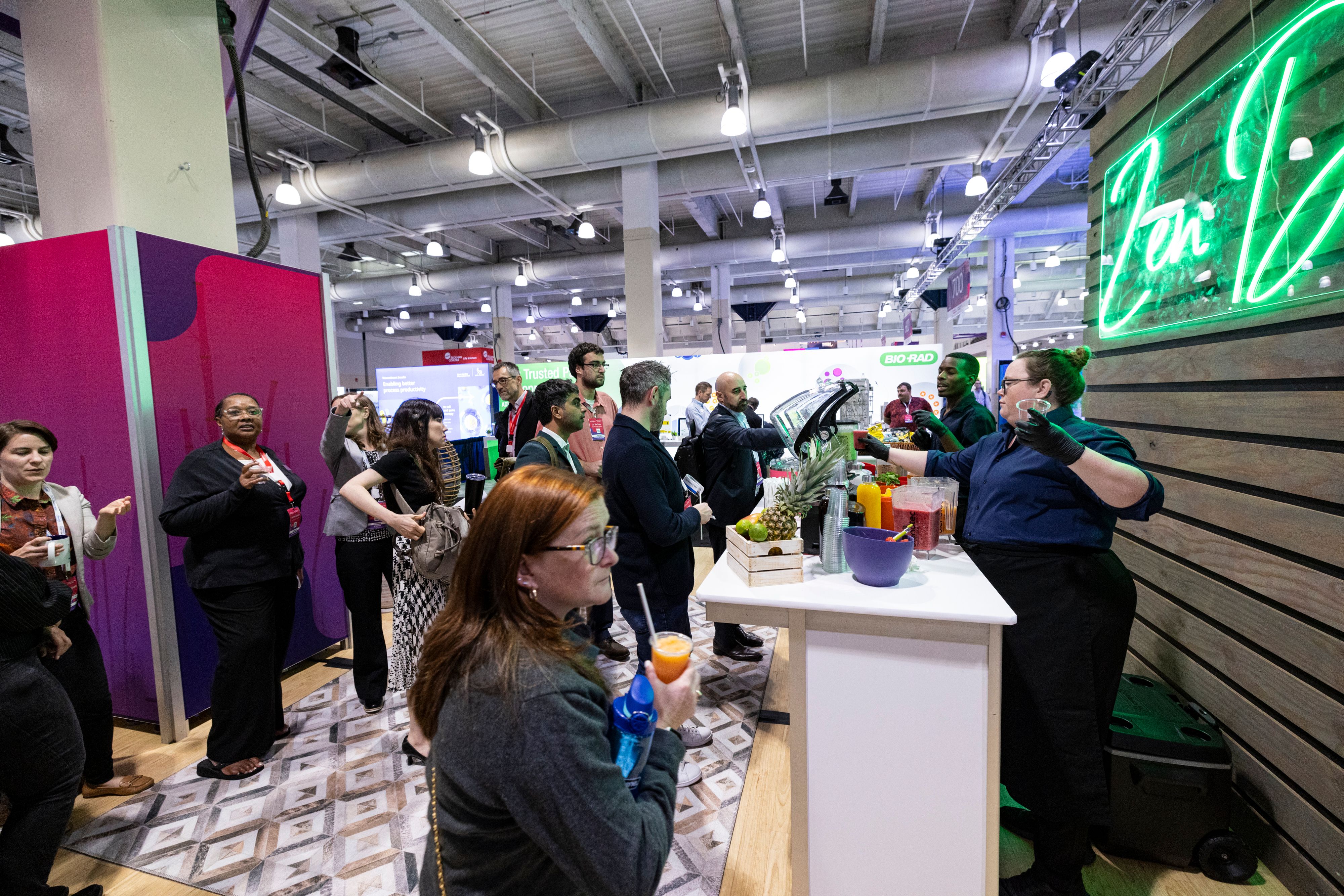 Biotech Week Boston attendees receive smoothies from a server at the Zen Den in the Exhibit Hall.